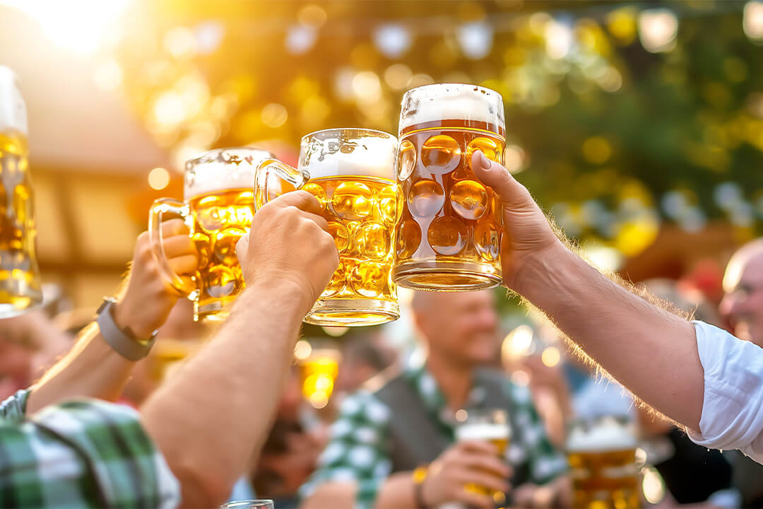 Männer stossen mit Bierkrügen im Biergarten an.