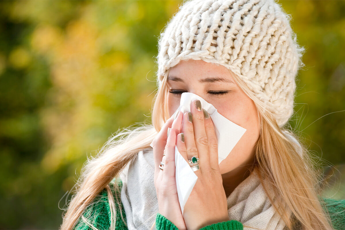 Blonde Frau putzt sich die Nase.