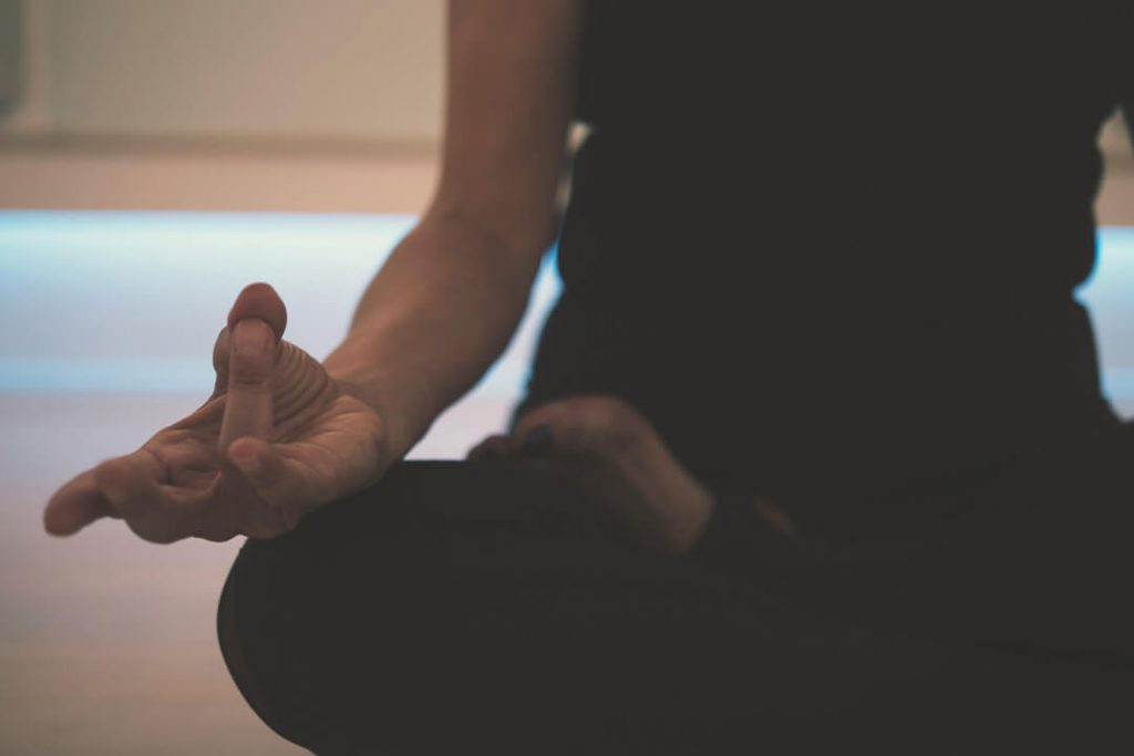 Meditierende Person, Fokus auf die entspannte Hand in klassischer Meditationspose.