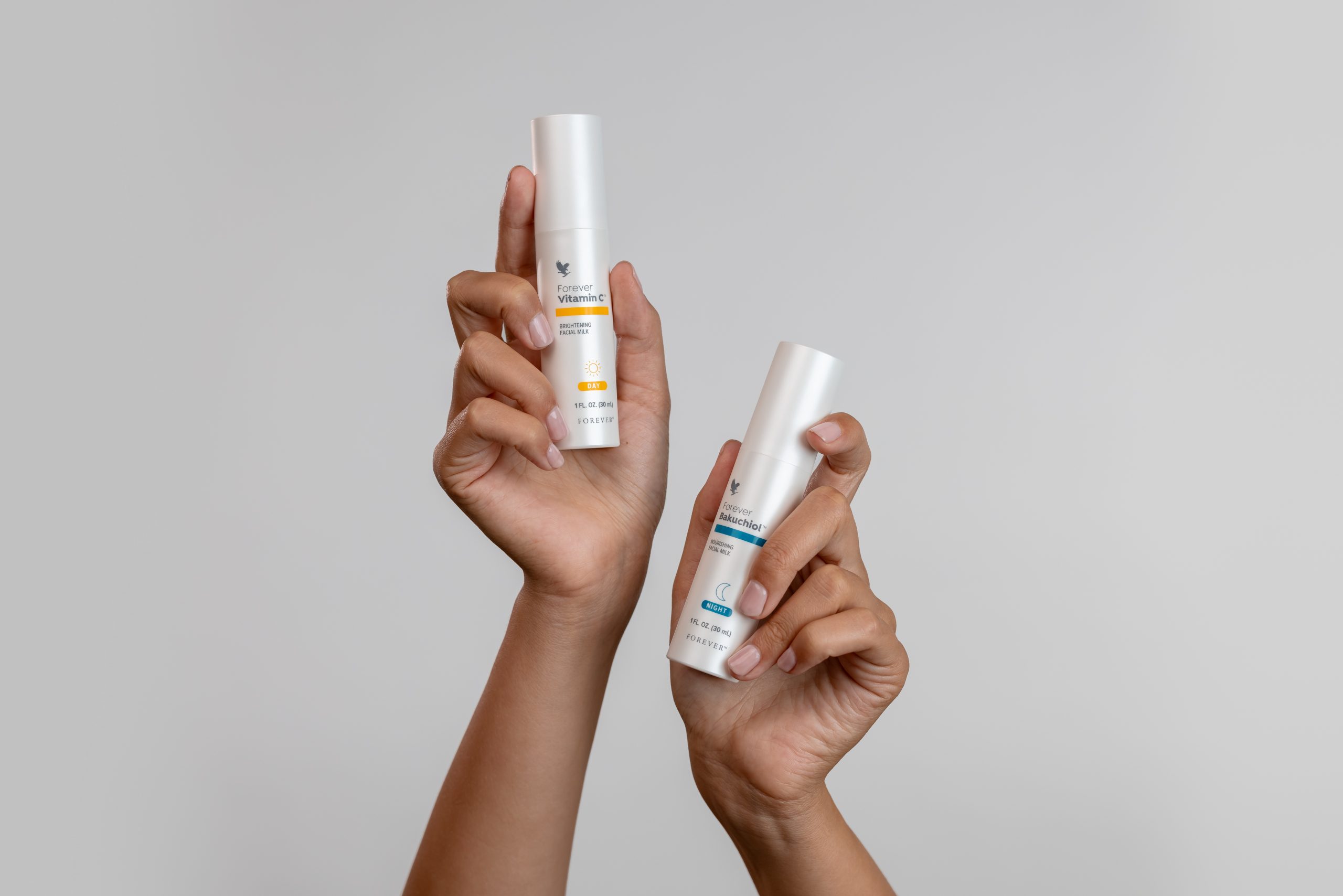 Forever Vitamin C™ und Forever Bakuchiol™ Tages- und Nachtpflege in Händen gehalten – sanftes Pflegeduo für strahlende Haut.