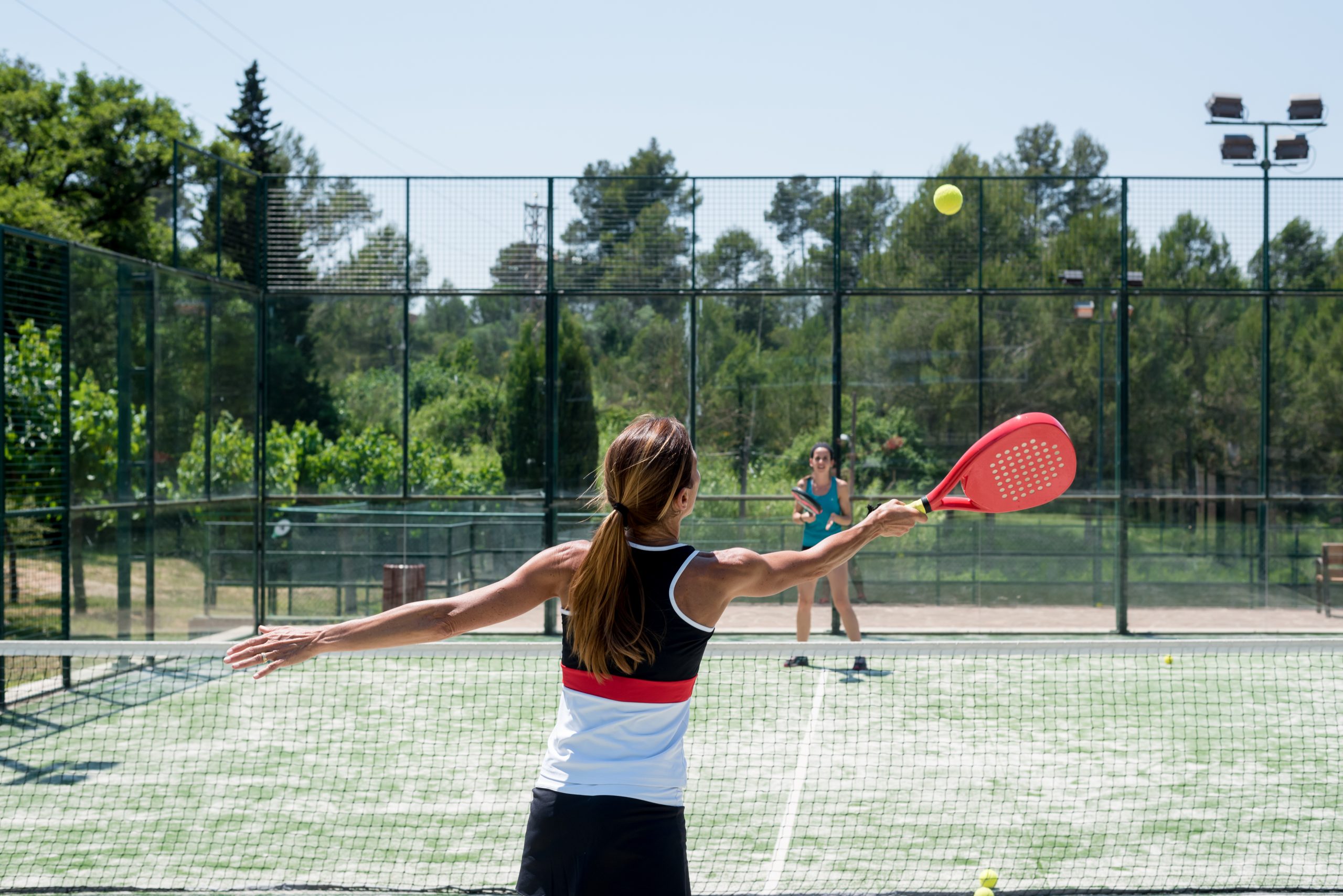 Eine Frau spielt mit einer anderen Person Padel