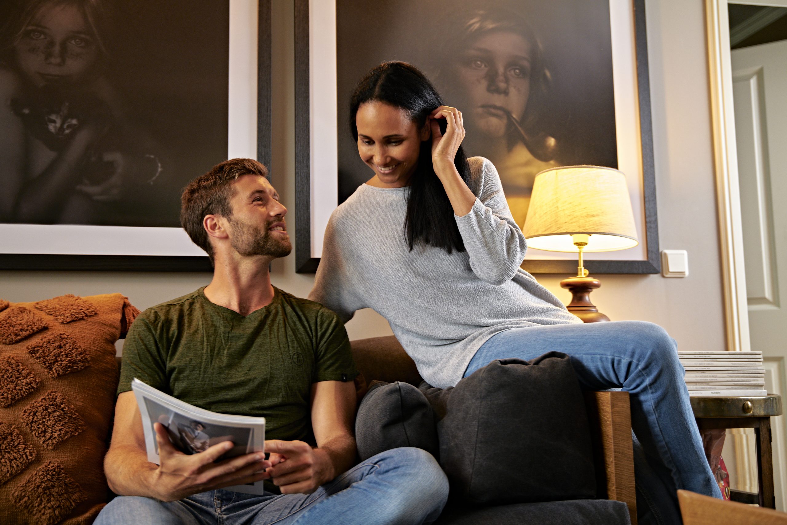 Eine Frau und ein Mann sitzen auf dem Sofa und sprechen über eine Brochüre.