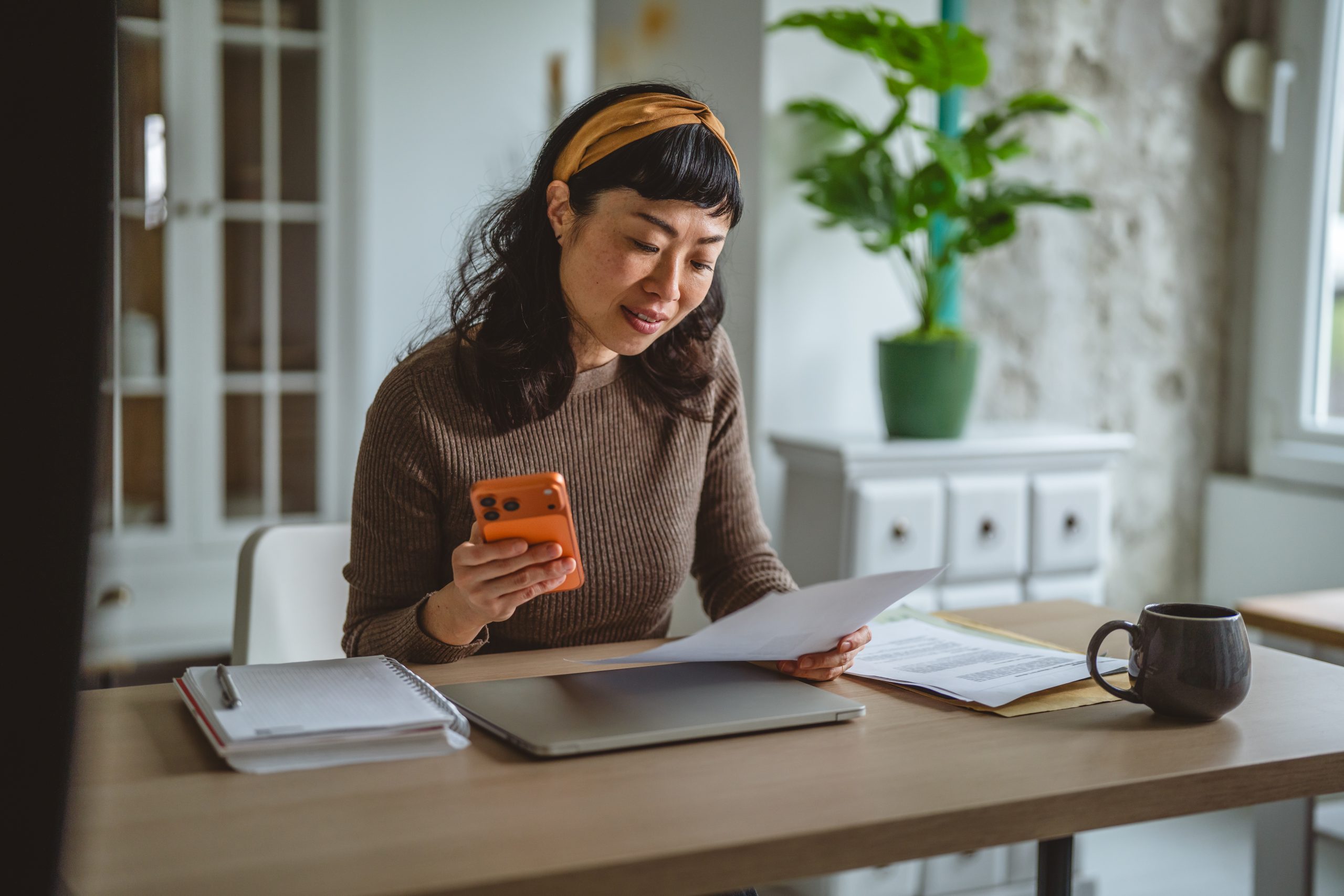 Eine Frau sitzt mit ihrem Handy vor ihren Network Marketing Business