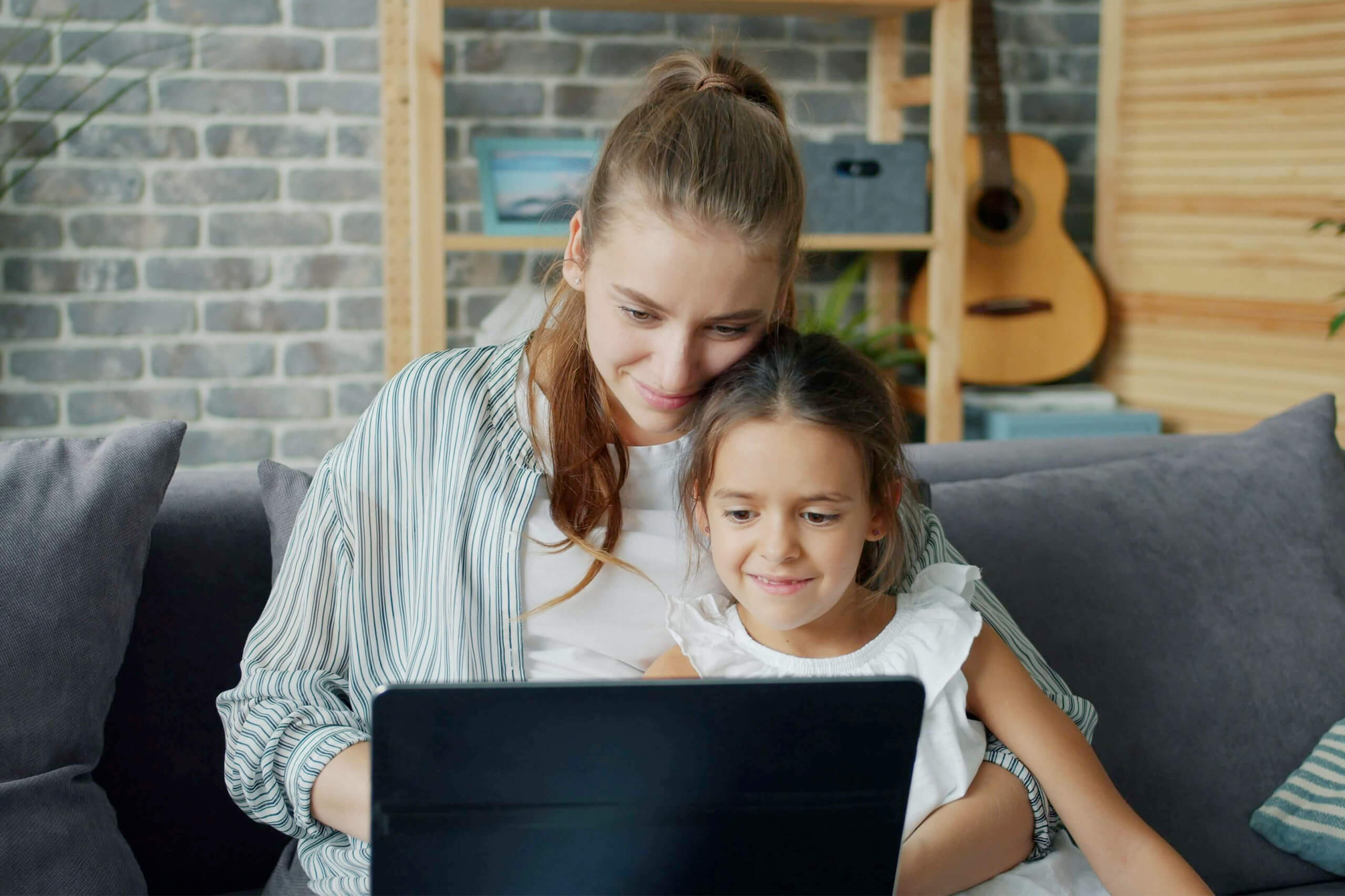 Eine Mutter arbeitet am Laptop mit ihrer Tochter im Arm.